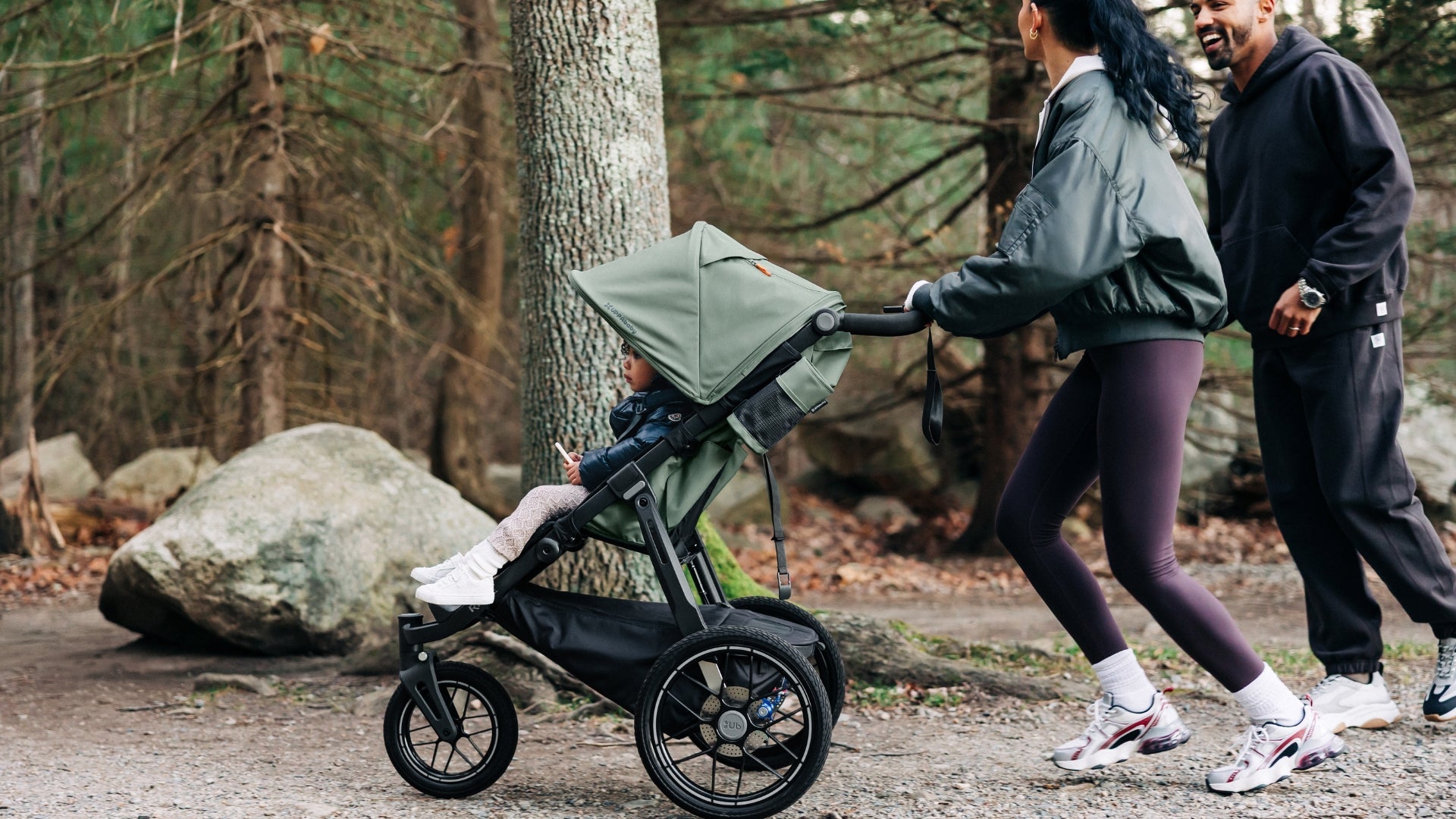 Parents out running on hiking trail with toddler in UPPAbaby Ridge V2