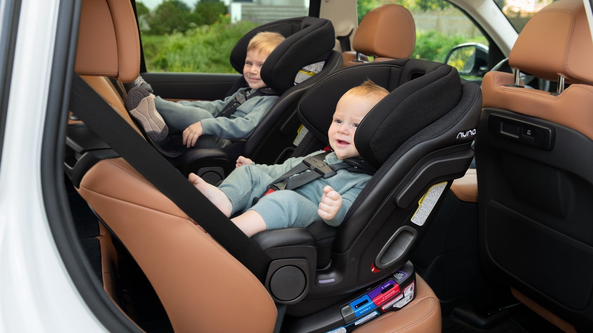 Two siblings riding in two Nuna EXEC Next car seats both rear facing in vehicle