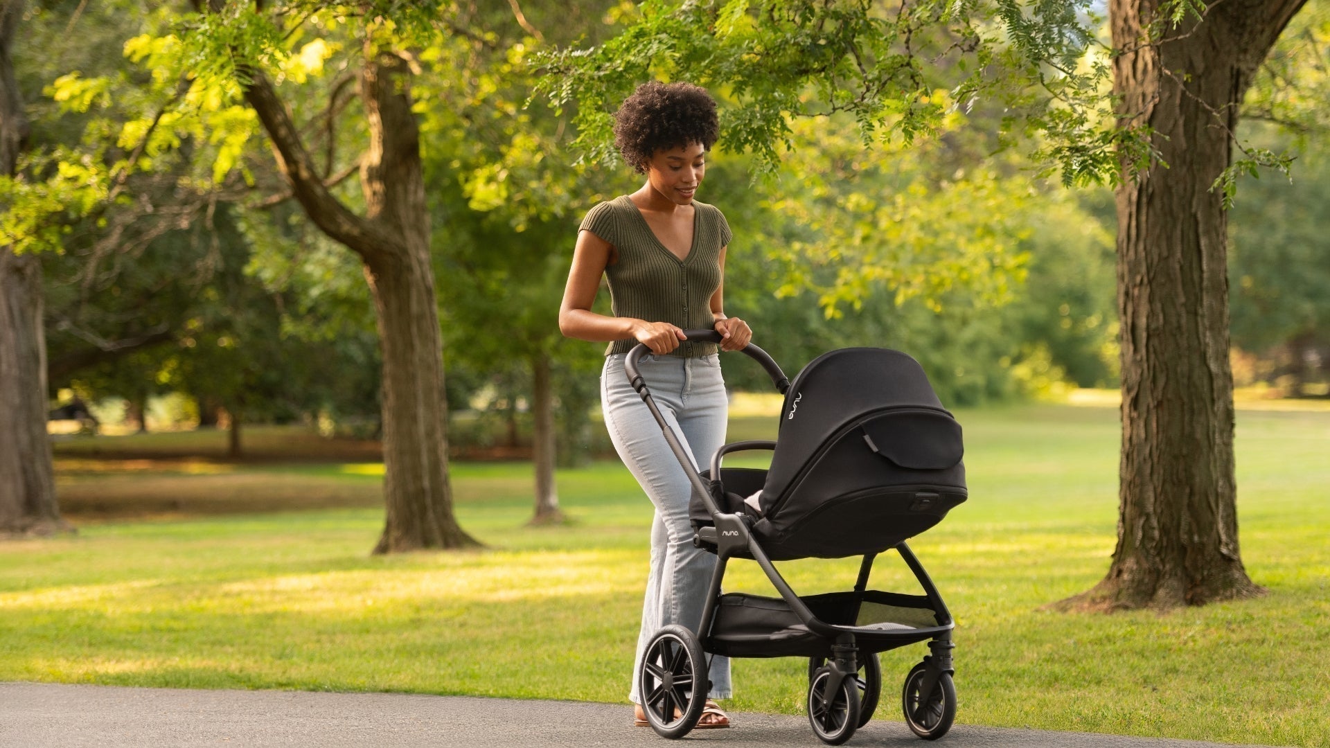Mom pushing newborn in Nuna TRIV lx with stroller seat in fully reclined carraige mode