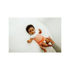 Orange Knit Arms Out Sleep Sack - Baby Lying on White Surface, Wide Angle View | Bambi Baby